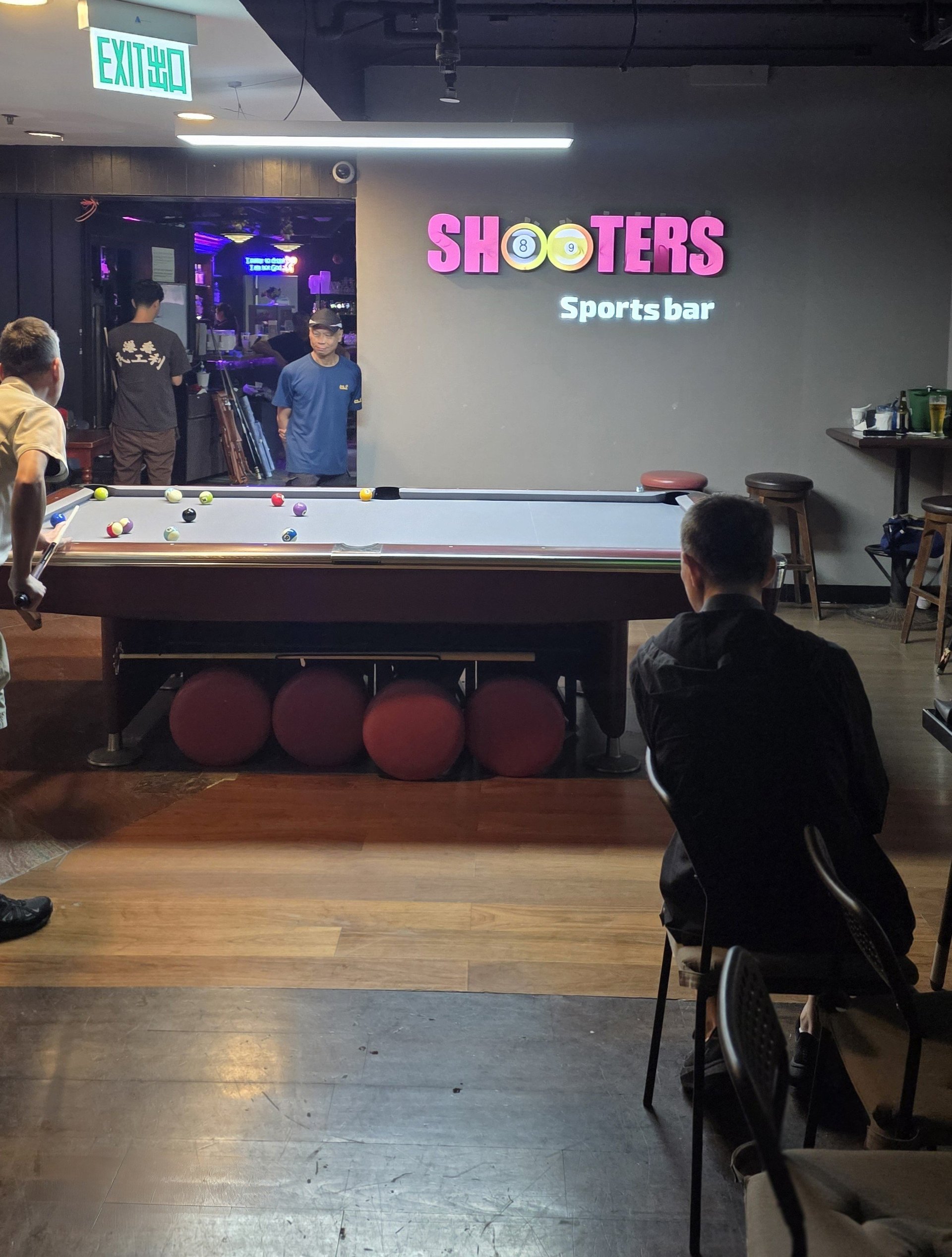 Interior of Shooters Sports Bar with pool table, patrons, and neon signage in modern venue